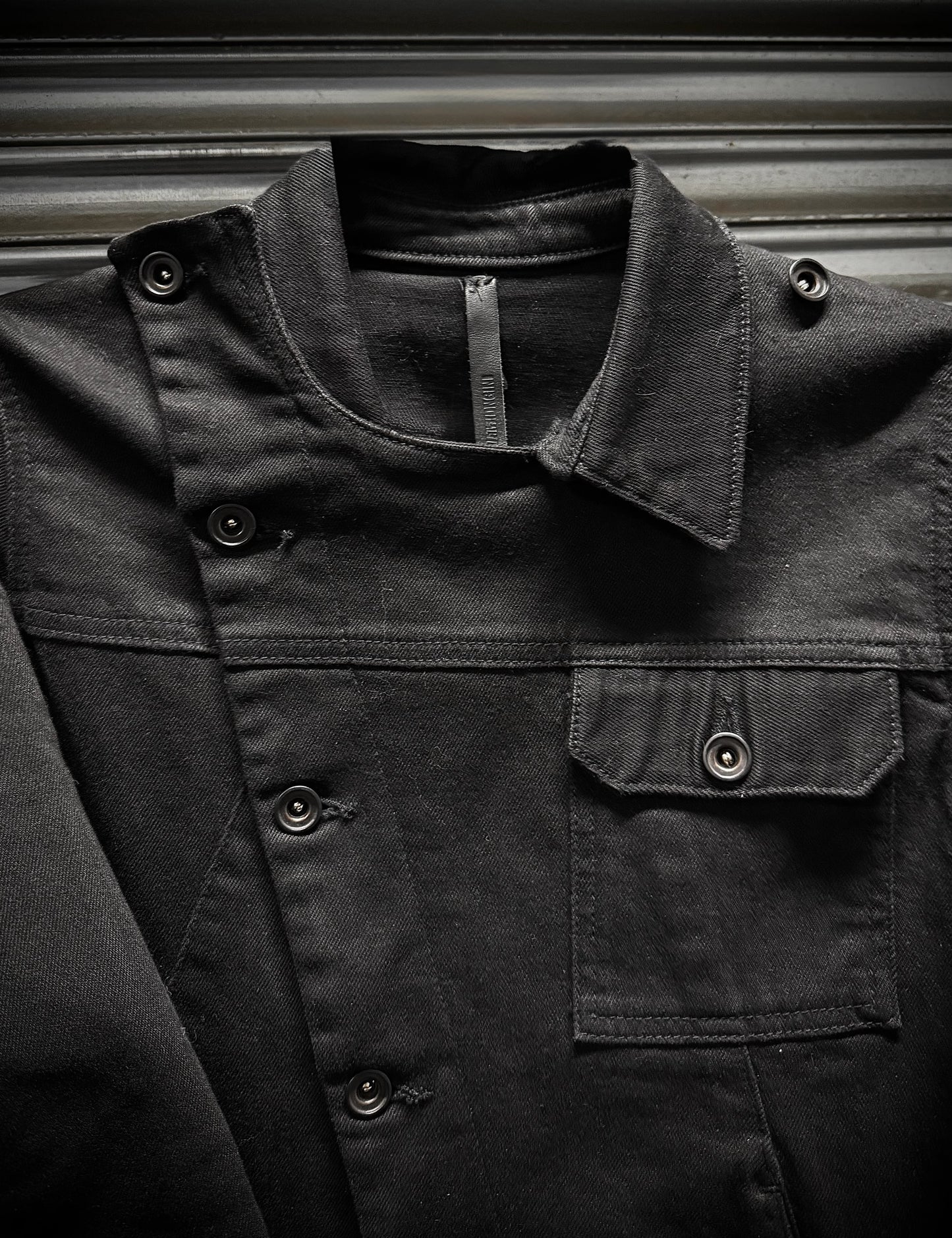Close-up of a dark jacket with buttons and a zipper on a metallic surface
