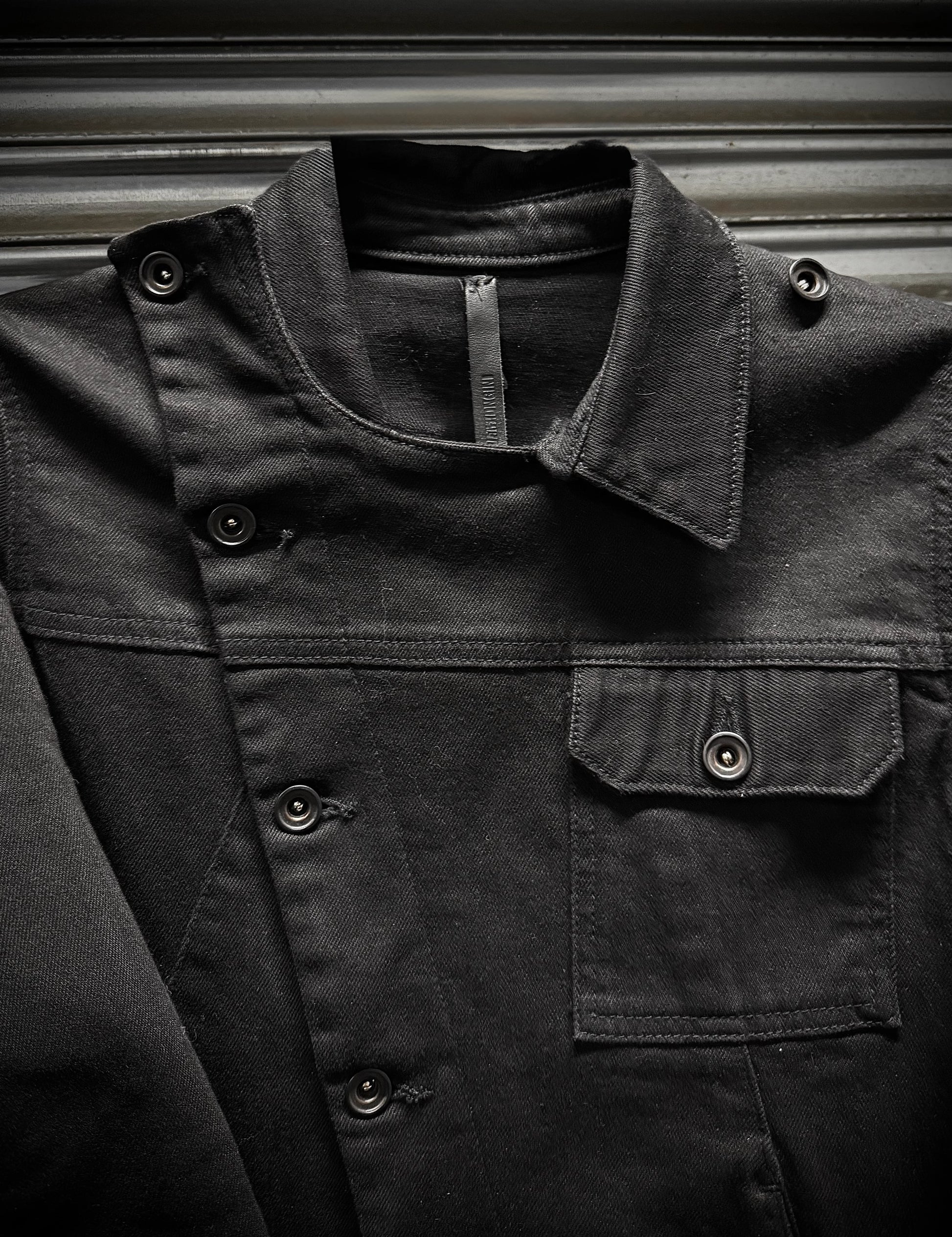 Close-up of a dark jacket with buttons and a zipper on a metallic surface