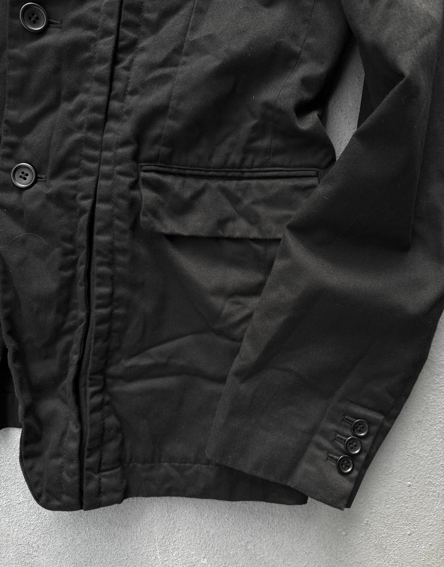 Close-up of a black jacket with buttons on a light gray background