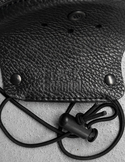 Black leather pouch with a strap on a textured surface