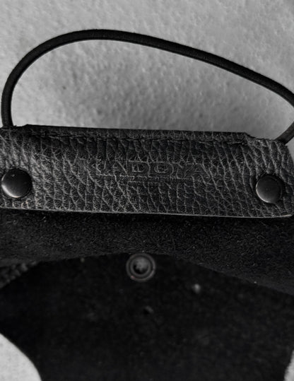 Close-up of a textured black leather strap with metal fasteners on a light gray background
