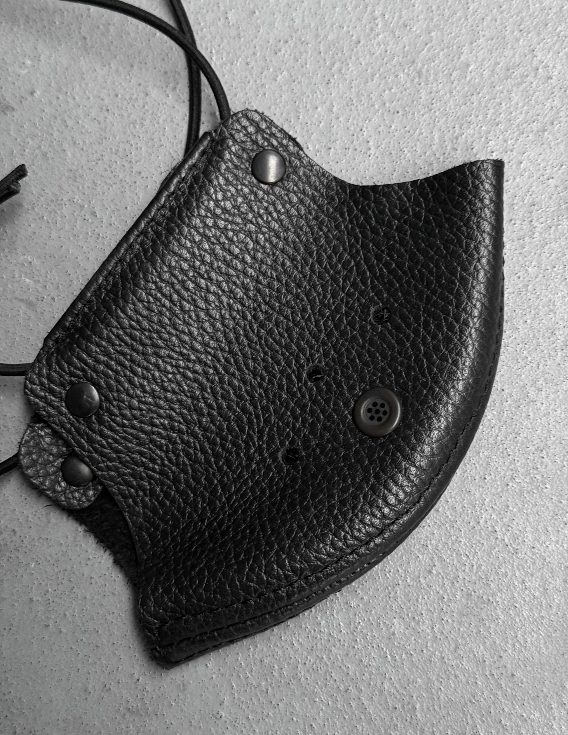 Black leather mask with button details on a gray background