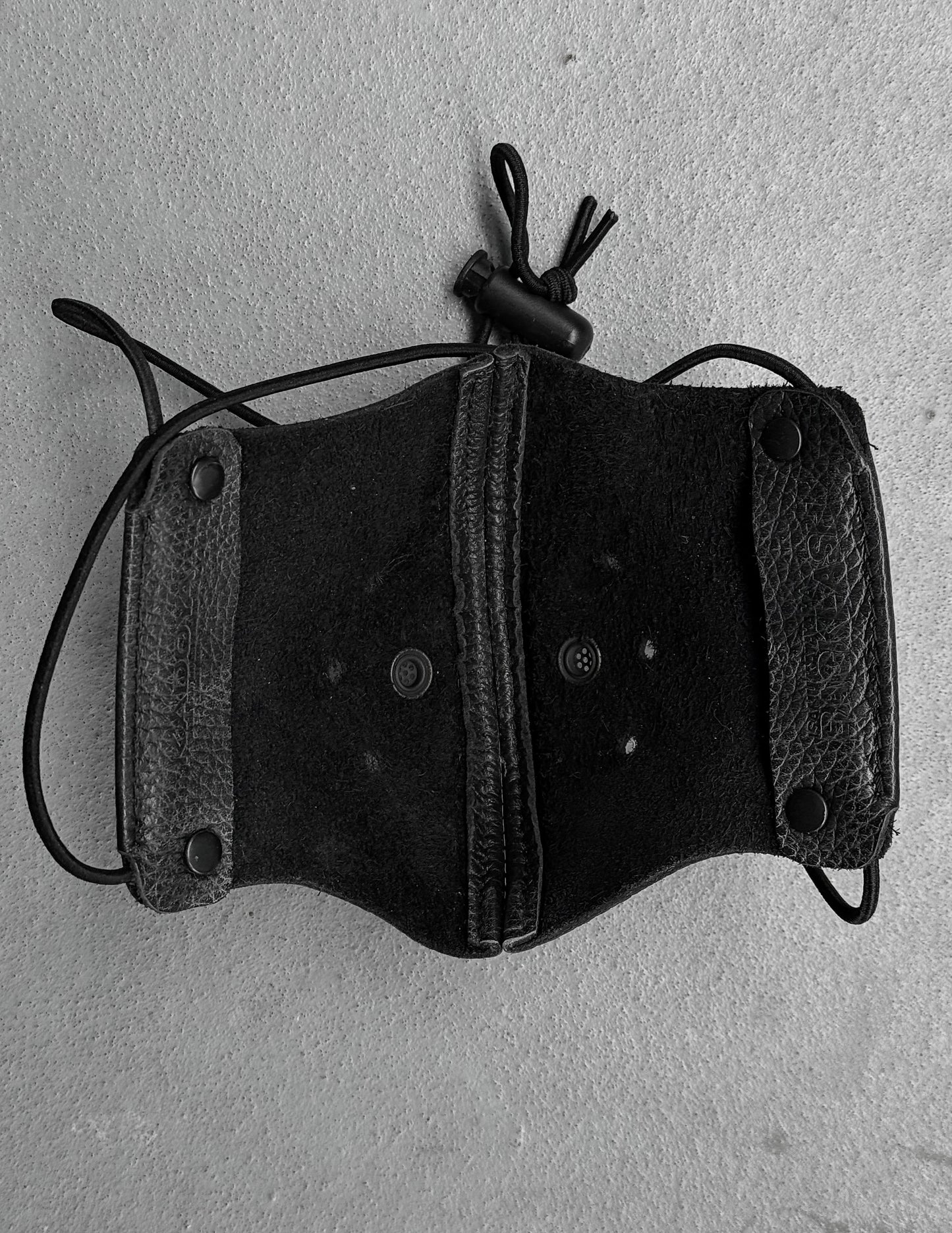 Black leather holster with a rope on a gray background