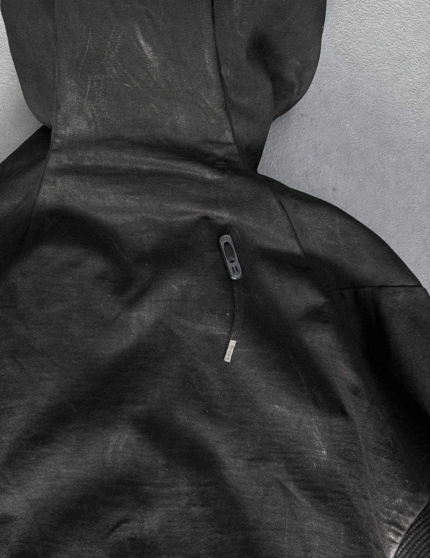 Close-up of a black hooded jacket with a zipper on a gray background