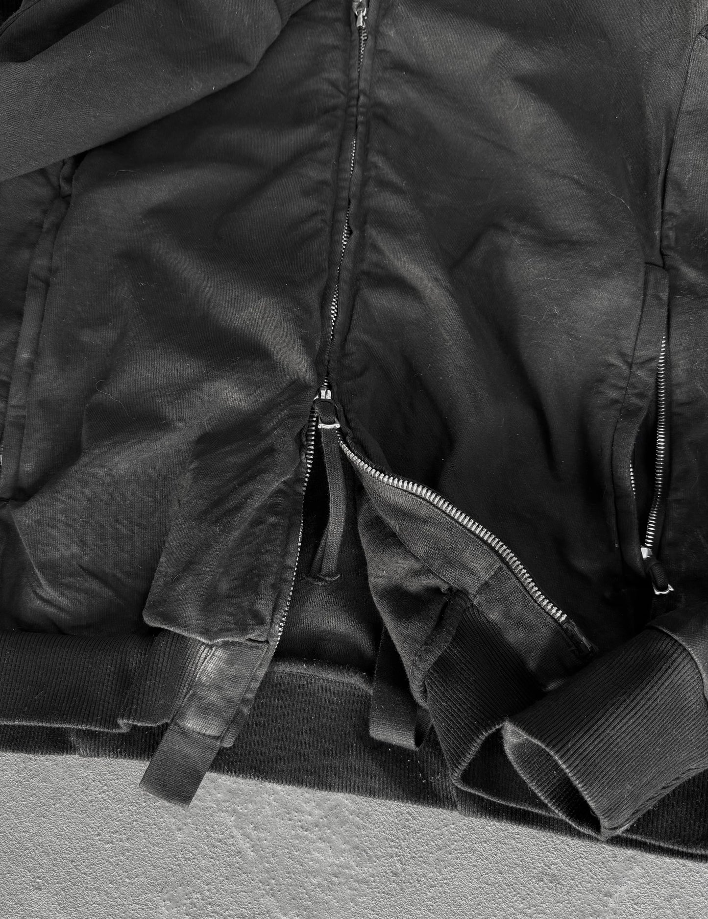 Close-up of a black jacket with zippers on a gray surface