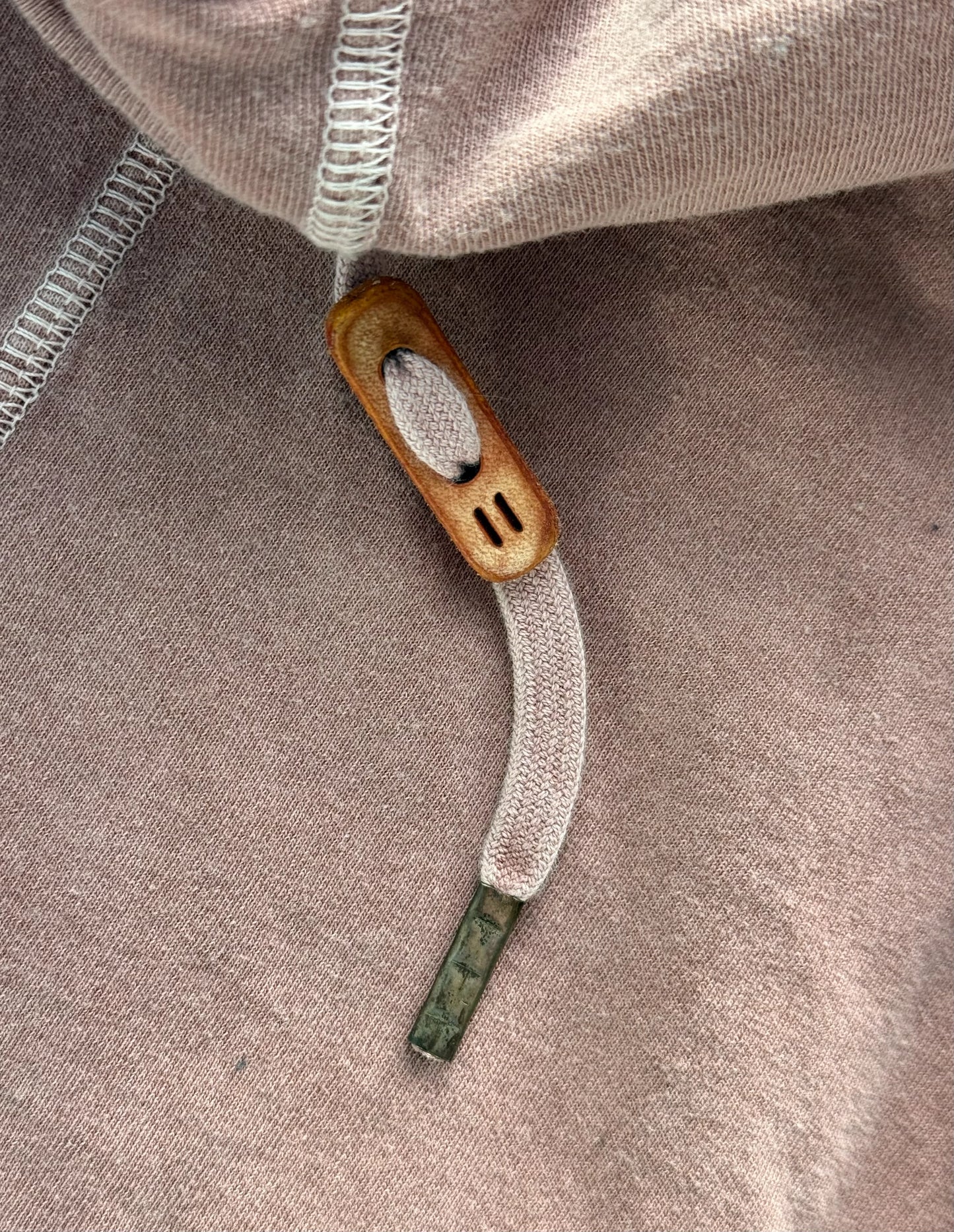 Close-up of a beige hoodie with a drawstring and zipper