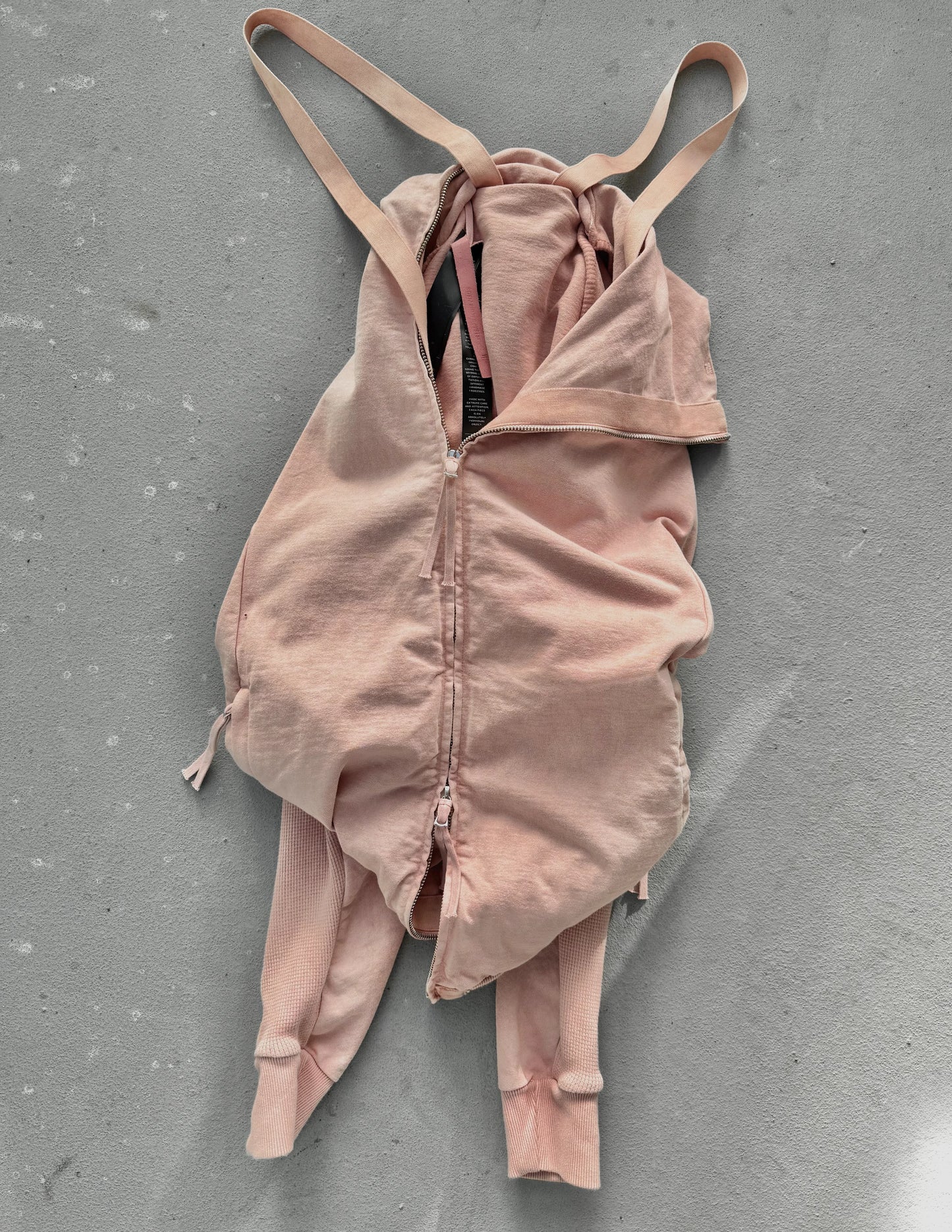 Pink bodysuit with thin straps on a gray surface
