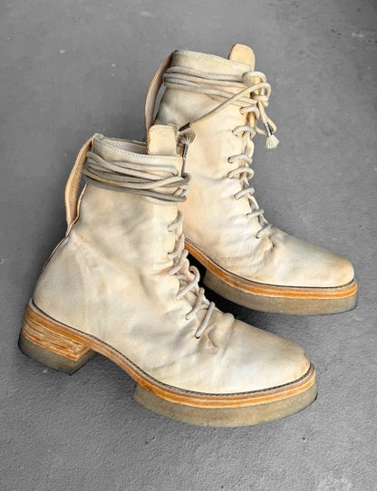 Pair of worn white boots on a gray background