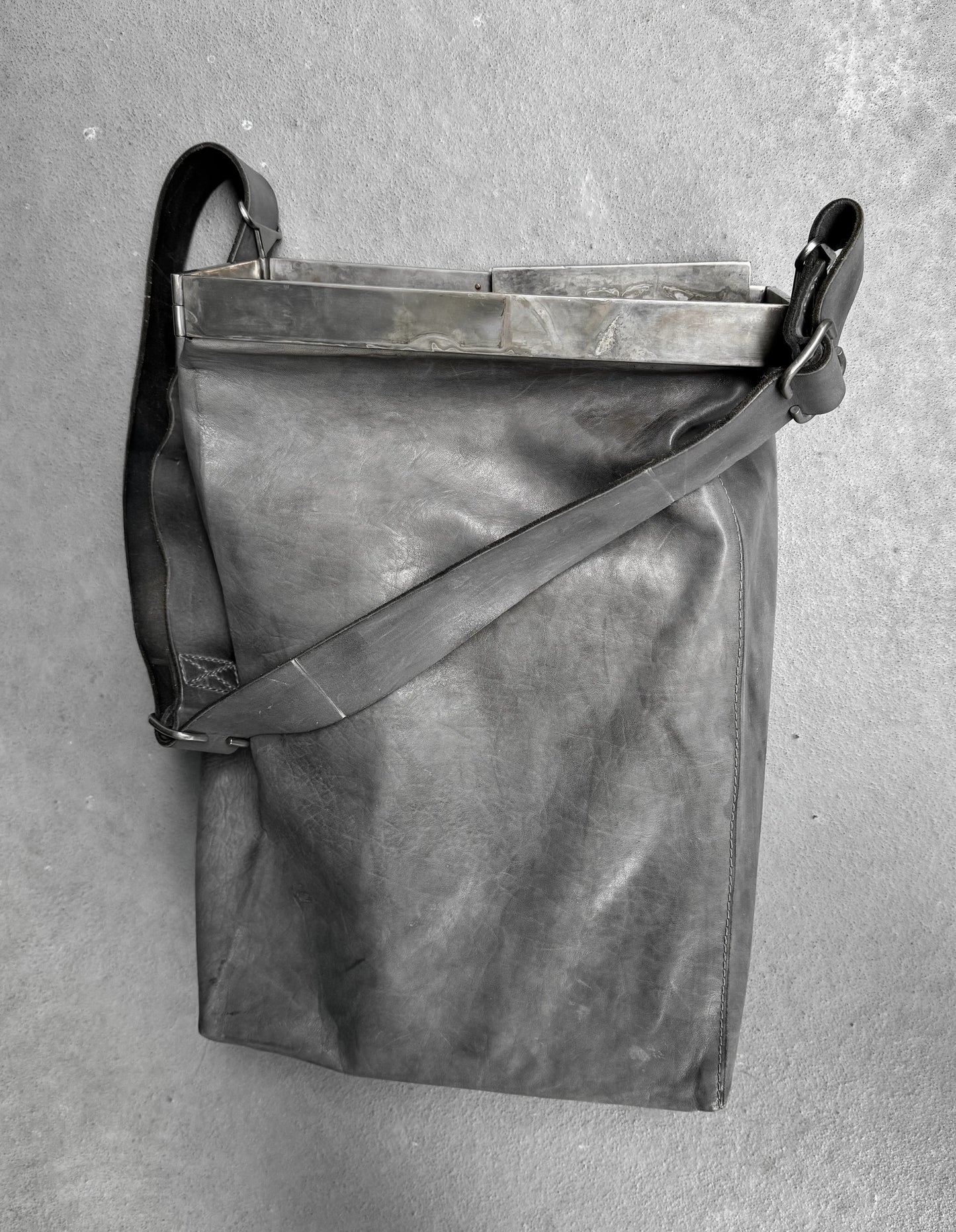 Gray leather bag with a strap on a gray background