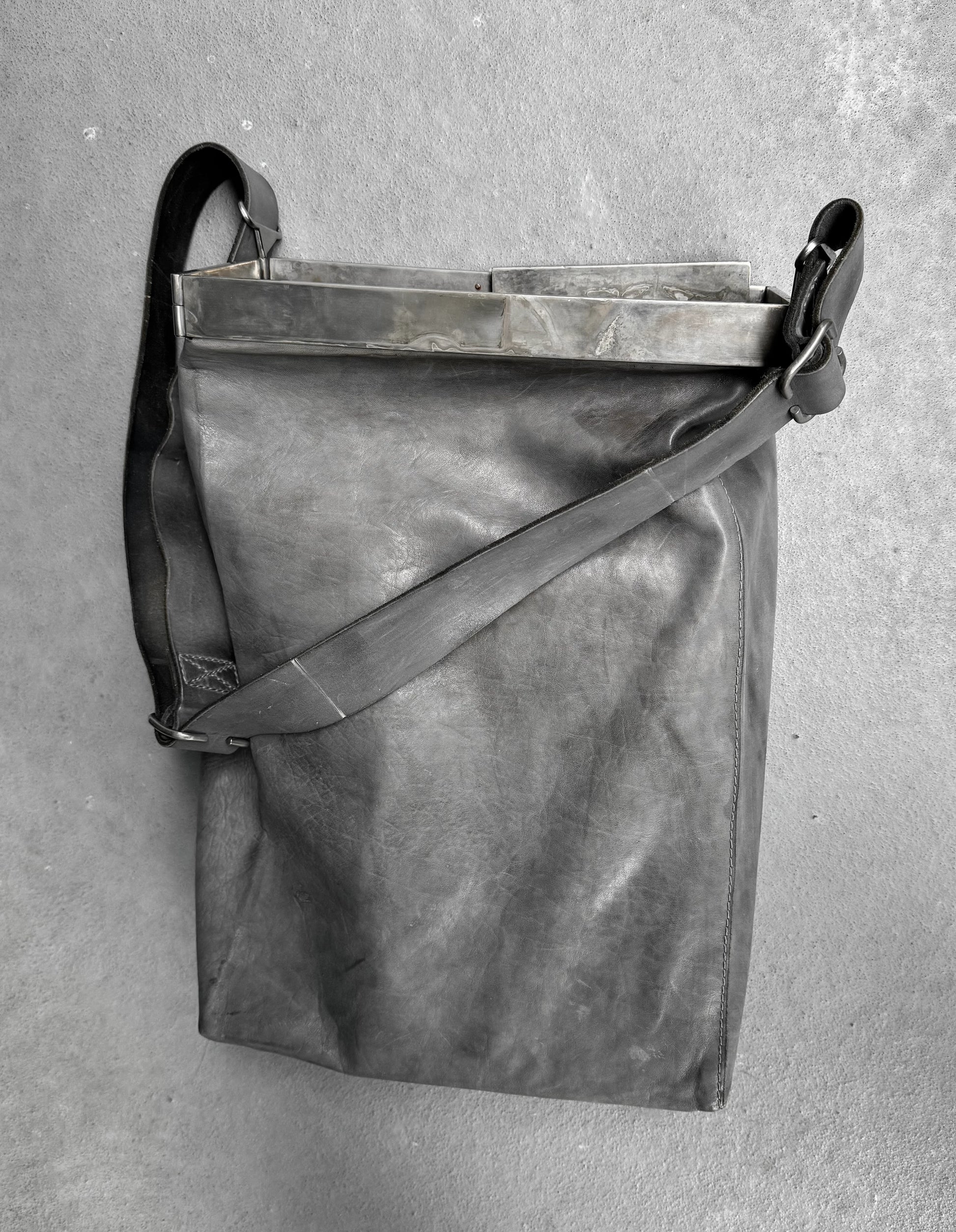 Gray leather bag with a strap on a gray background