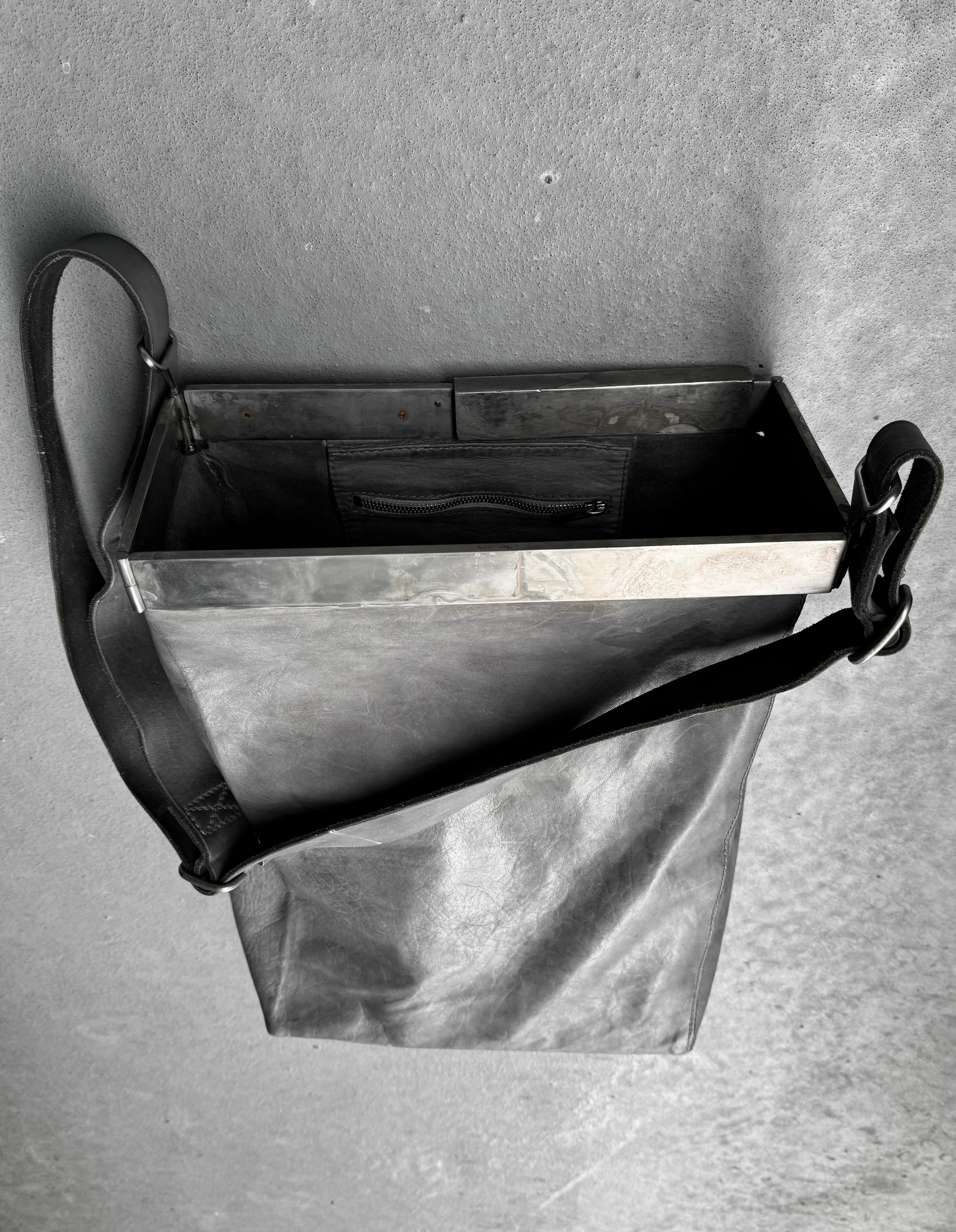 Metal dustpan with black handle on a gray background