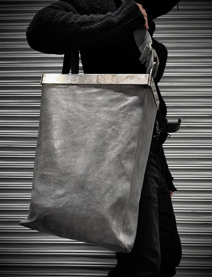 Person holding a large leather bag against a metallic shutter background