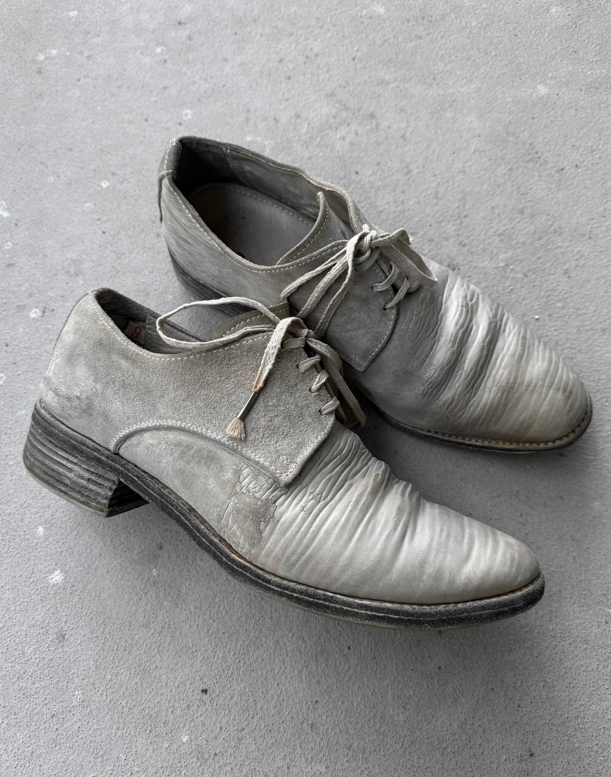 Pair of gray leather shoes on a concrete surface