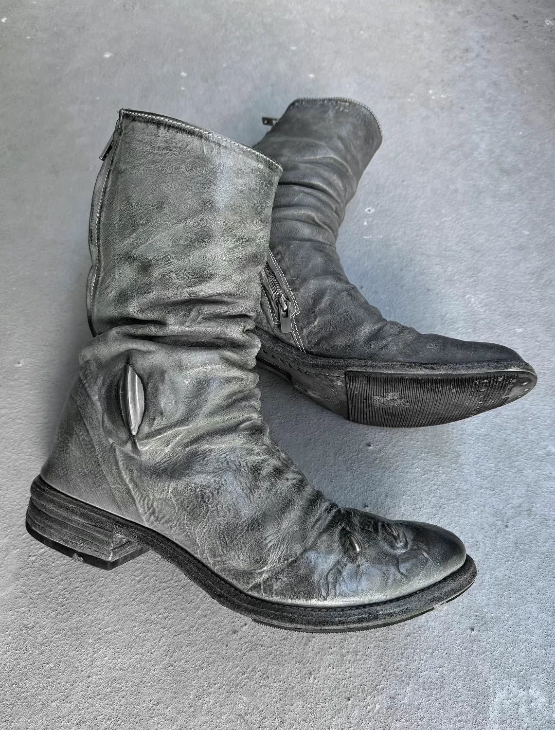 Pair of gray leather boots on a gray surface