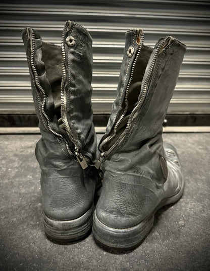 Pair of worn leather boots with zippers on a metallic surface