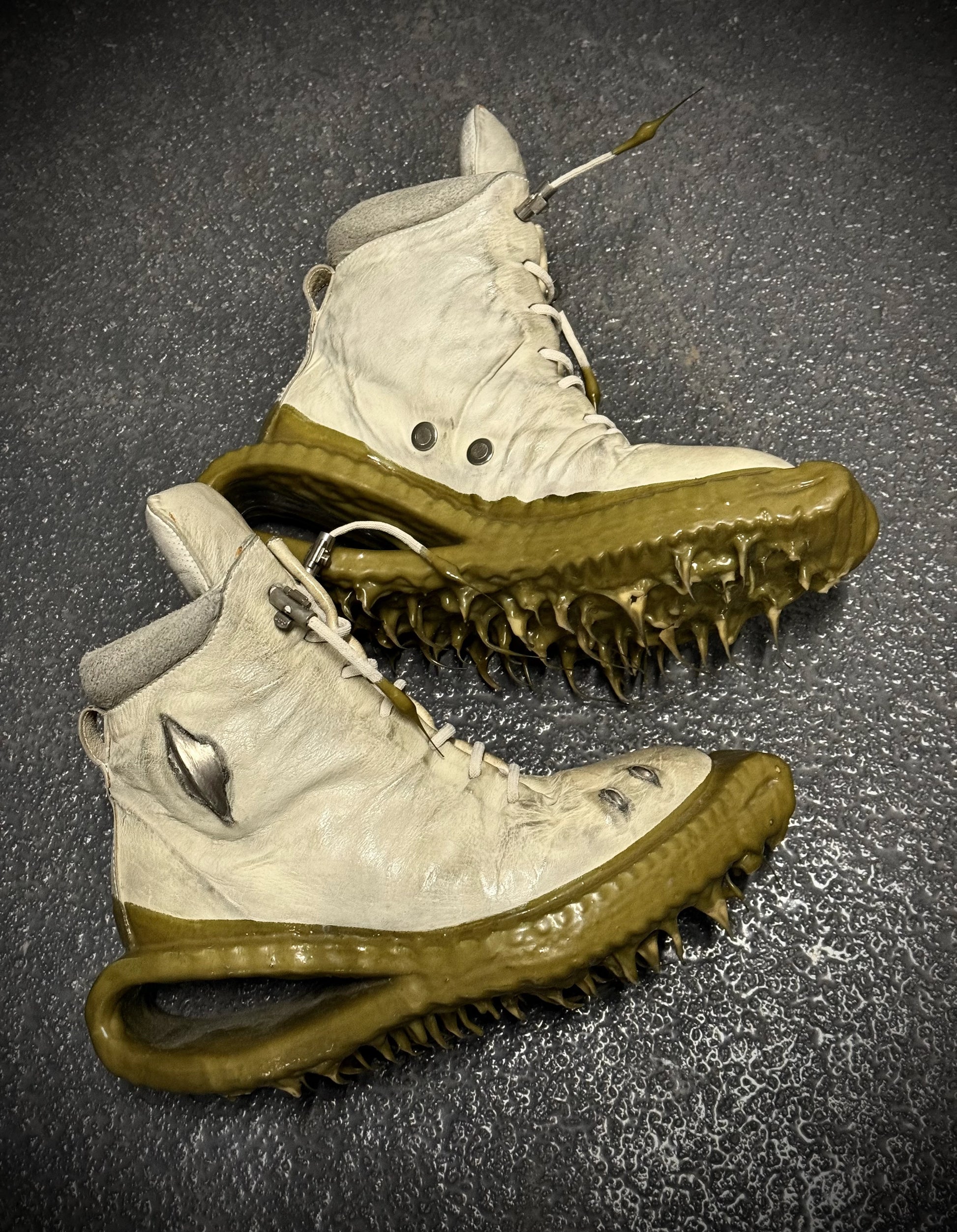 Pair of white and brown high-top sneakers with unique sole design on a dark textured background