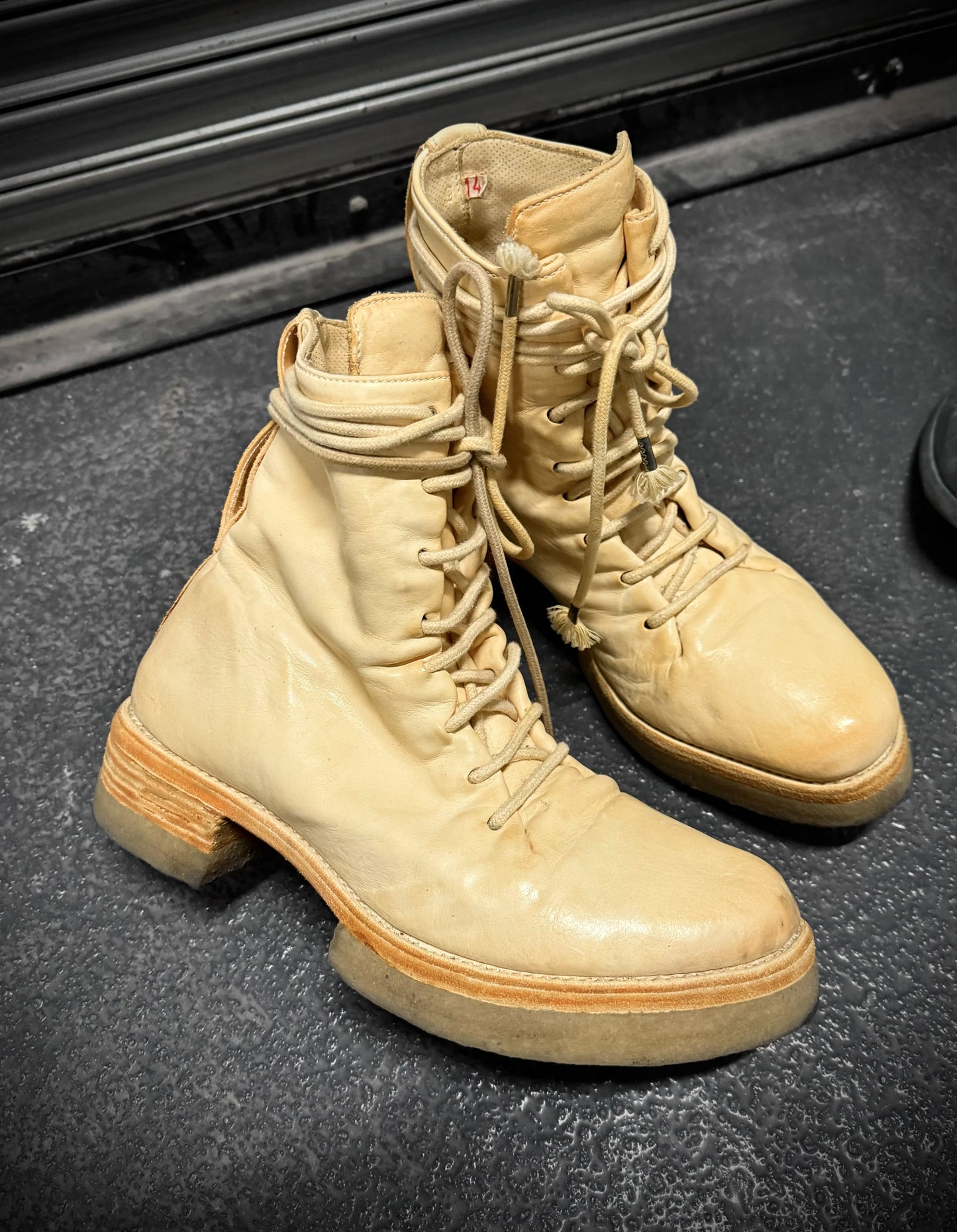 Pair of beige military boots on a black surface