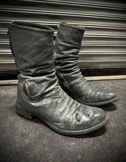 Pair of worn leather boots on a dark surface with a metallic background