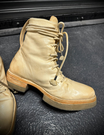 Pair of beige military boots on a textured surface