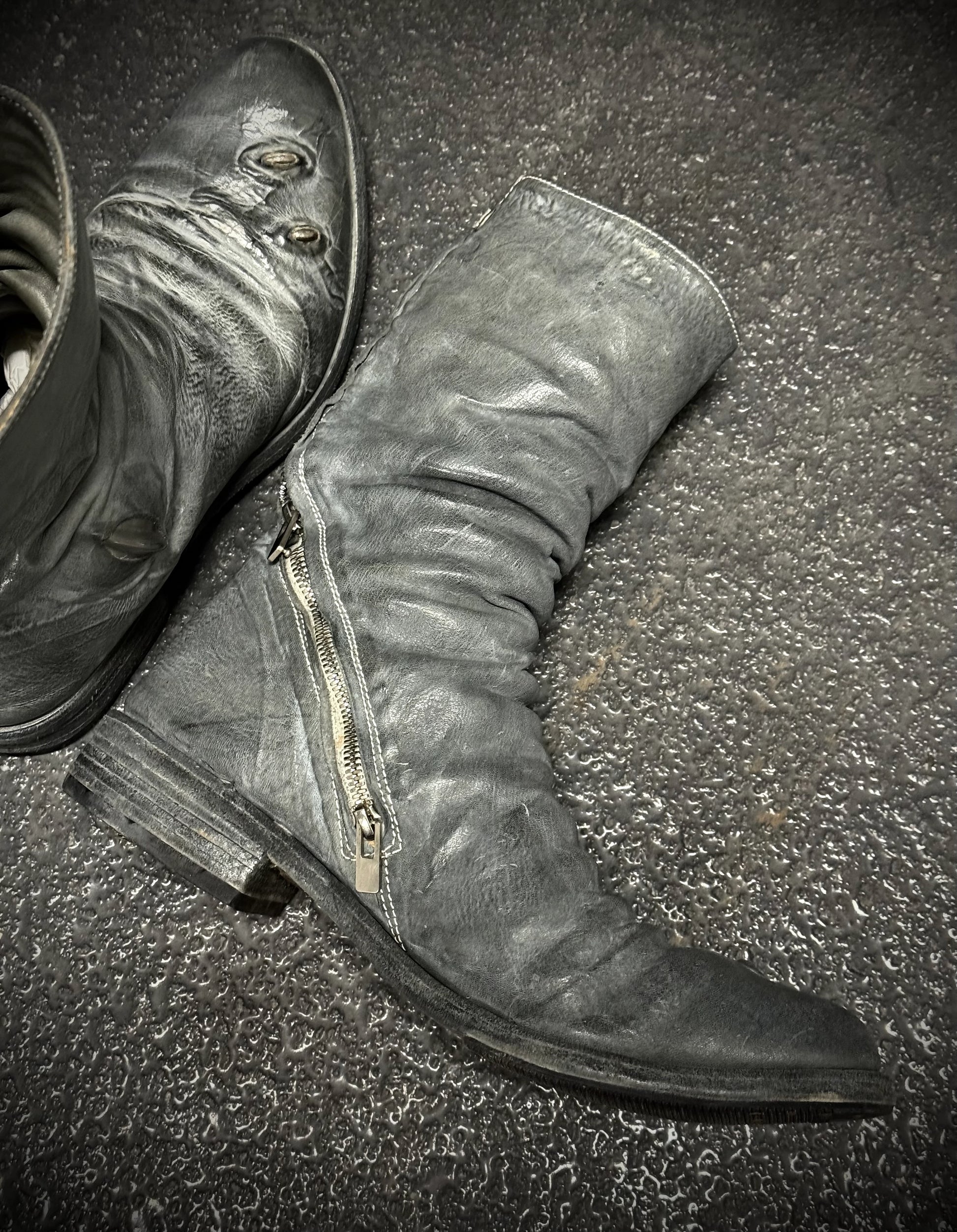 Pair of gray knee-high boots with zippers on a textured surface