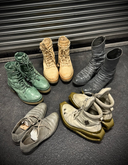 Collection of various boots on a dark surface with a metal shutter in the background