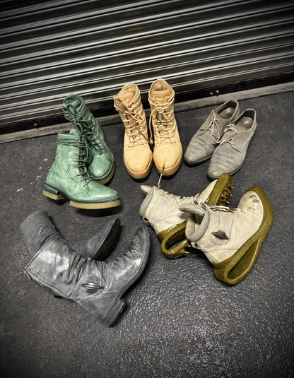 Collection of various boots on a dark surface with a metal shutter in the background