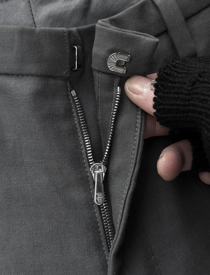 Close-up of a hand zipping up a dark coat with a focus on the zipper mechanism.