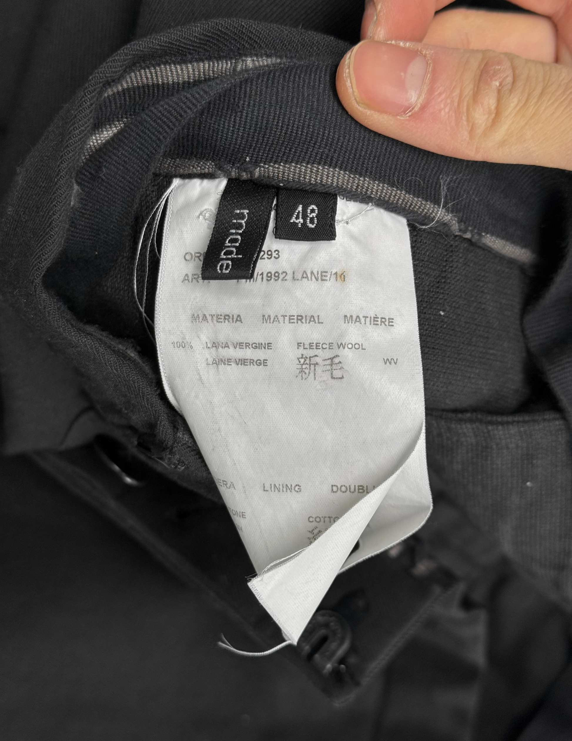Close-up of a clothing tag on a black jacket with visible text.