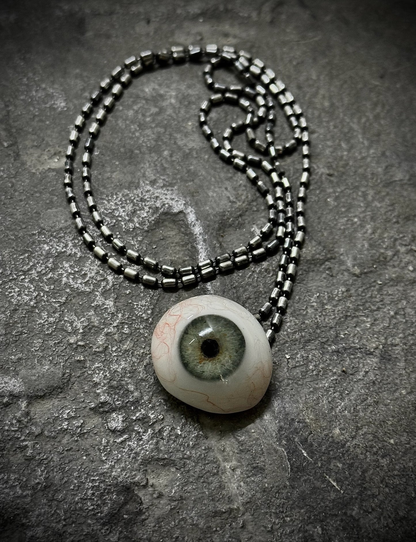 Necklace with an eye-shaped pendant on a textured surface