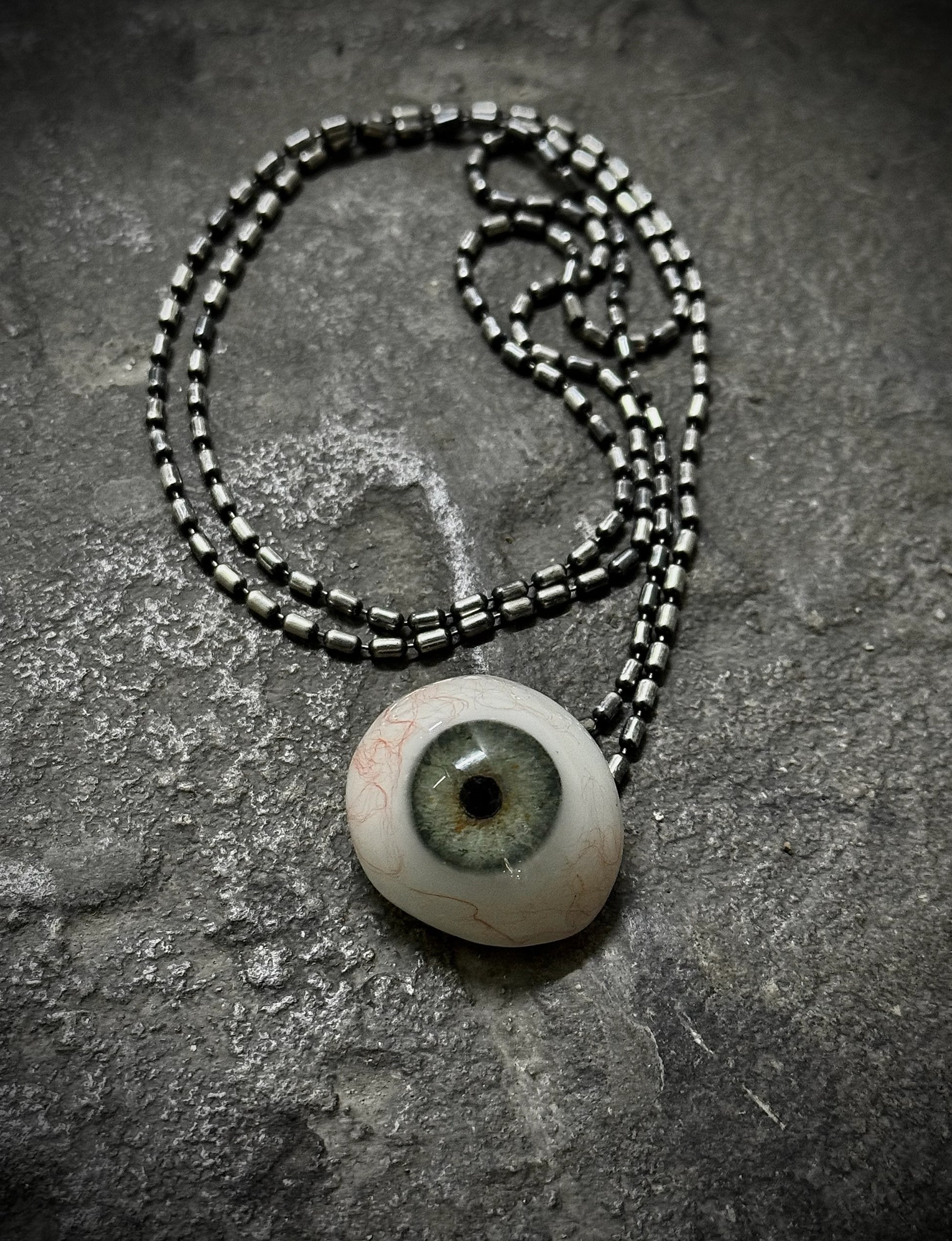 Necklace with an eye-shaped pendant on a textured surface