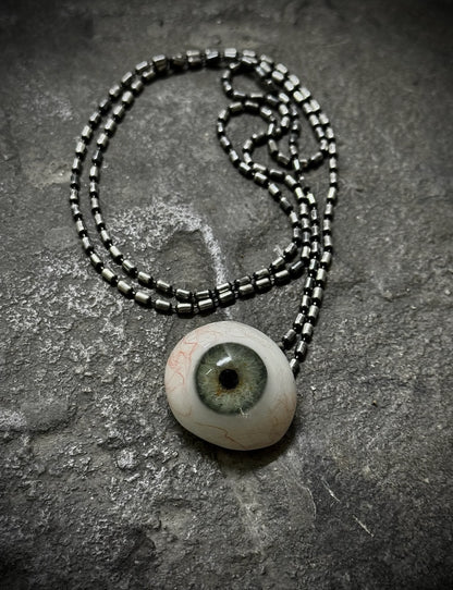 Necklace with an eye-shaped pendant on a textured surface