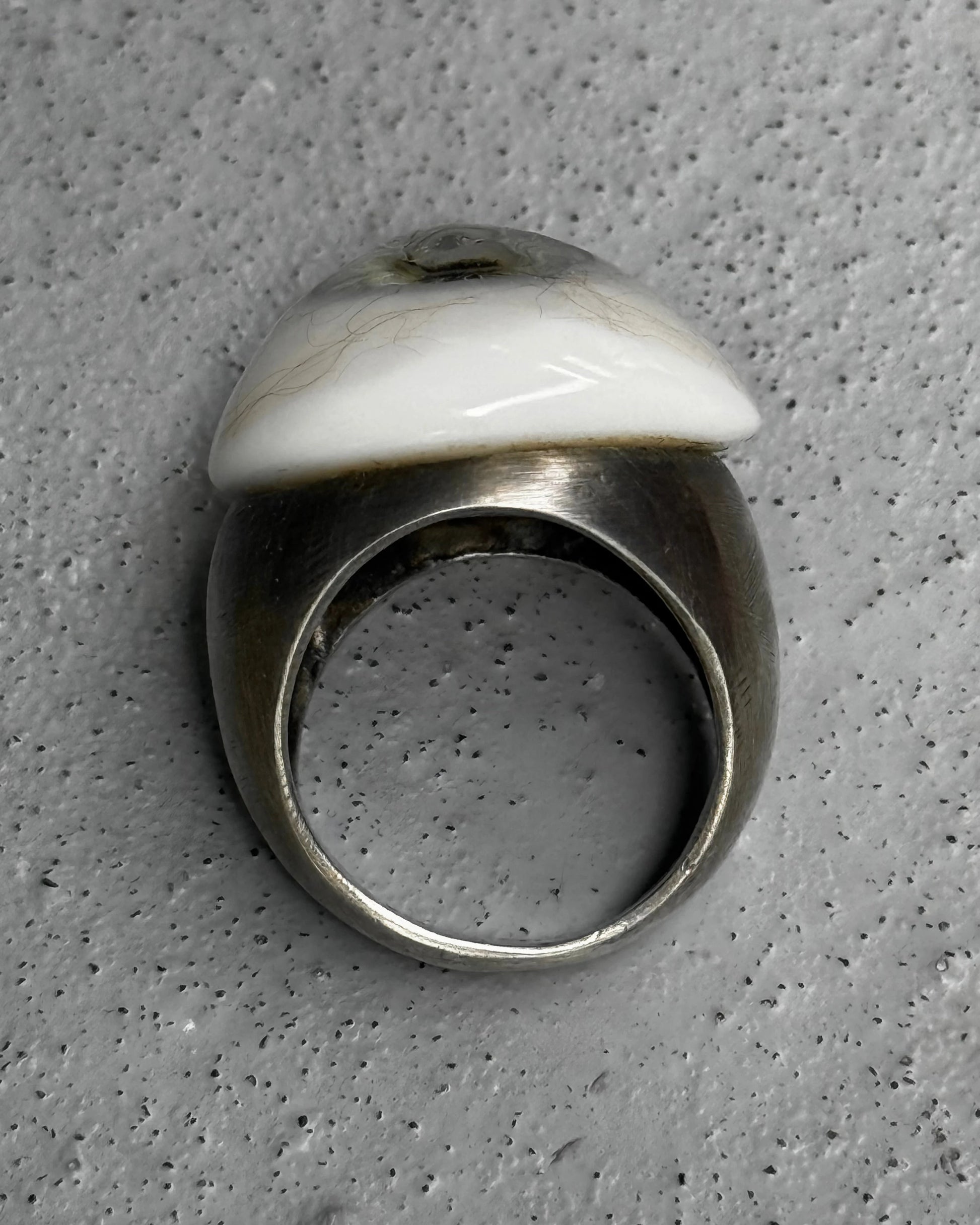 Silver ring with a white stone on a gray textured background