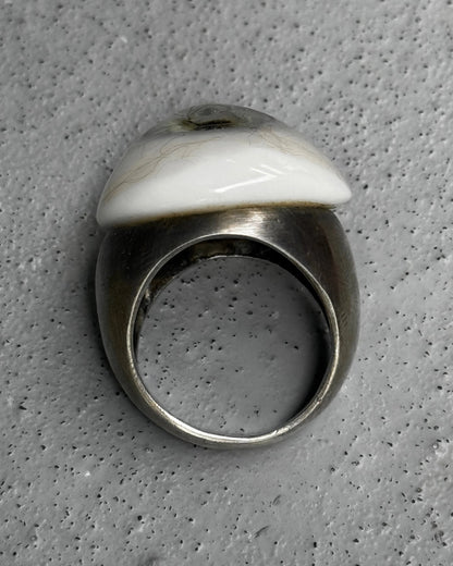Silver ring with a white stone on a gray textured background