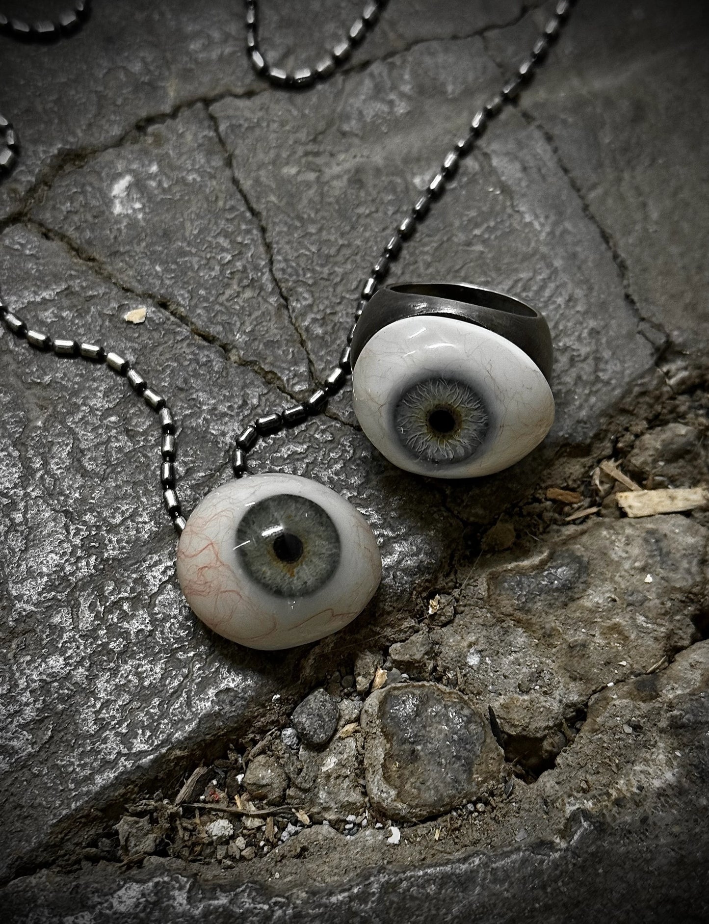 Two artificial eyes on a chain lying on a stone surface