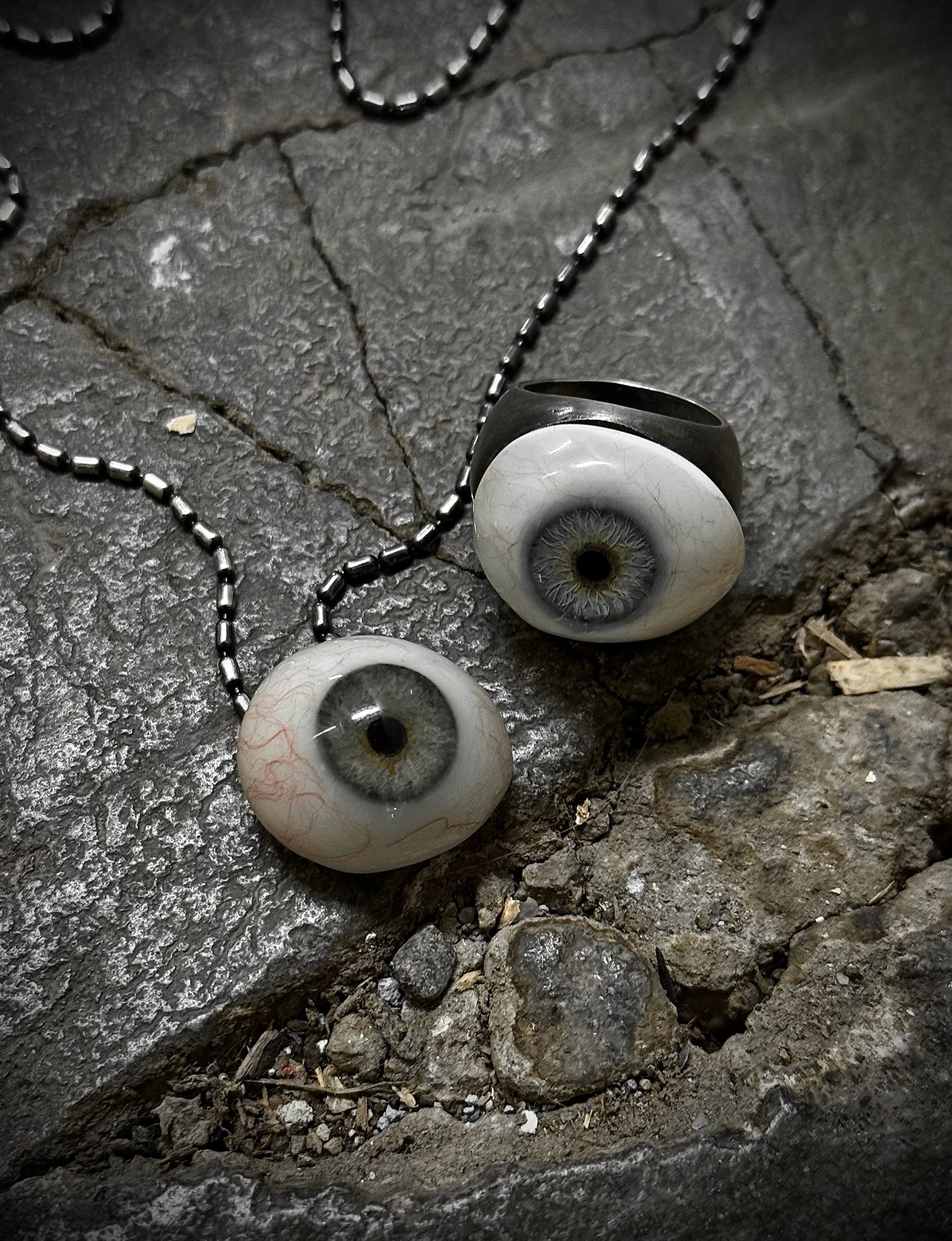 Two artificial eyes on a chain lying on a stone surface