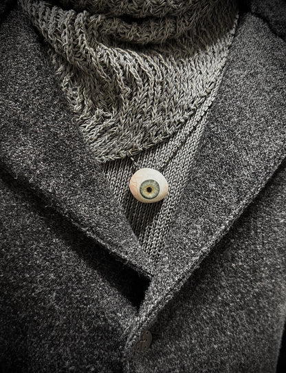 Close-up of a textured scarf and coat with a button, in grayscale.
