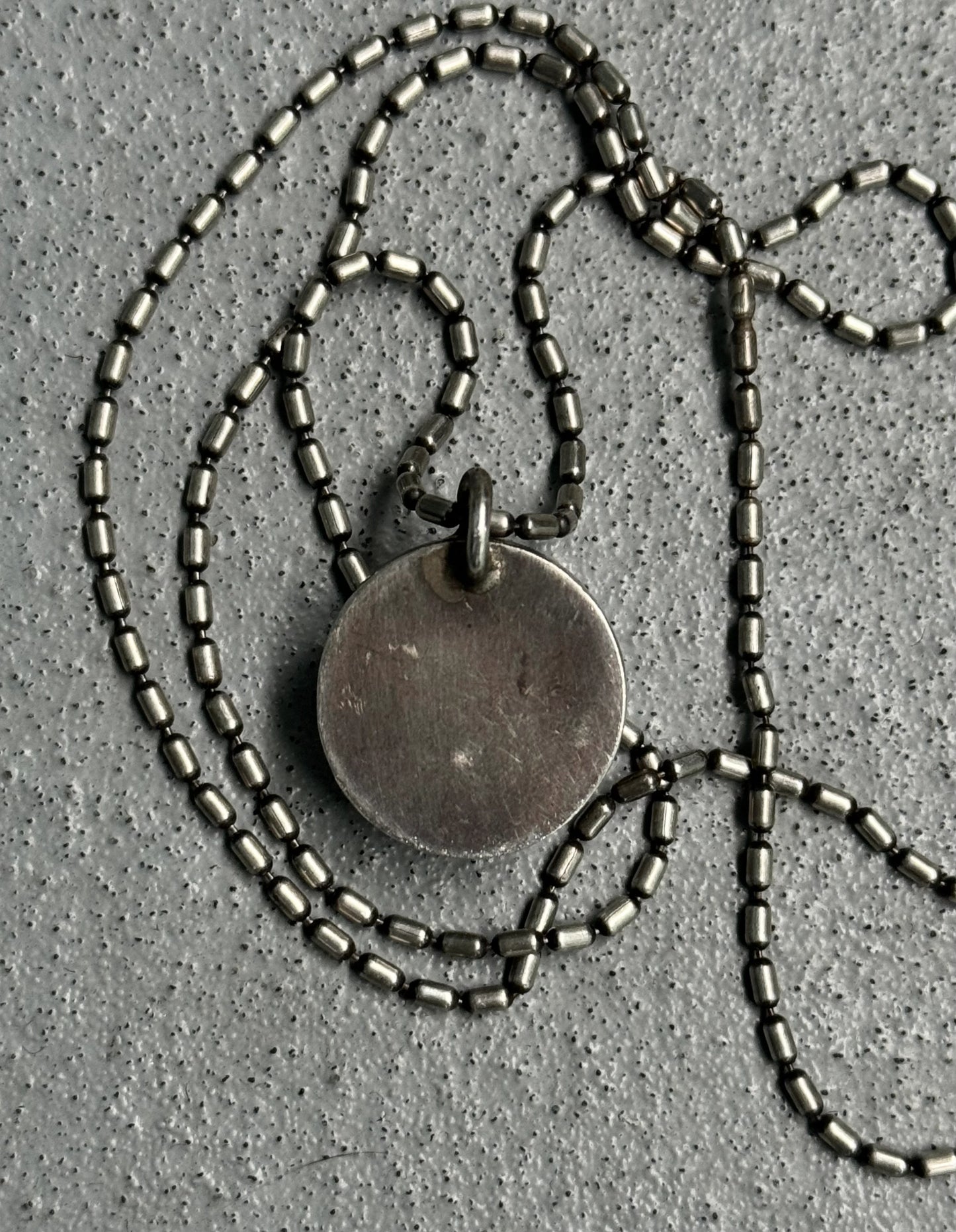 Necklace with a round pendant on a textured gray surface