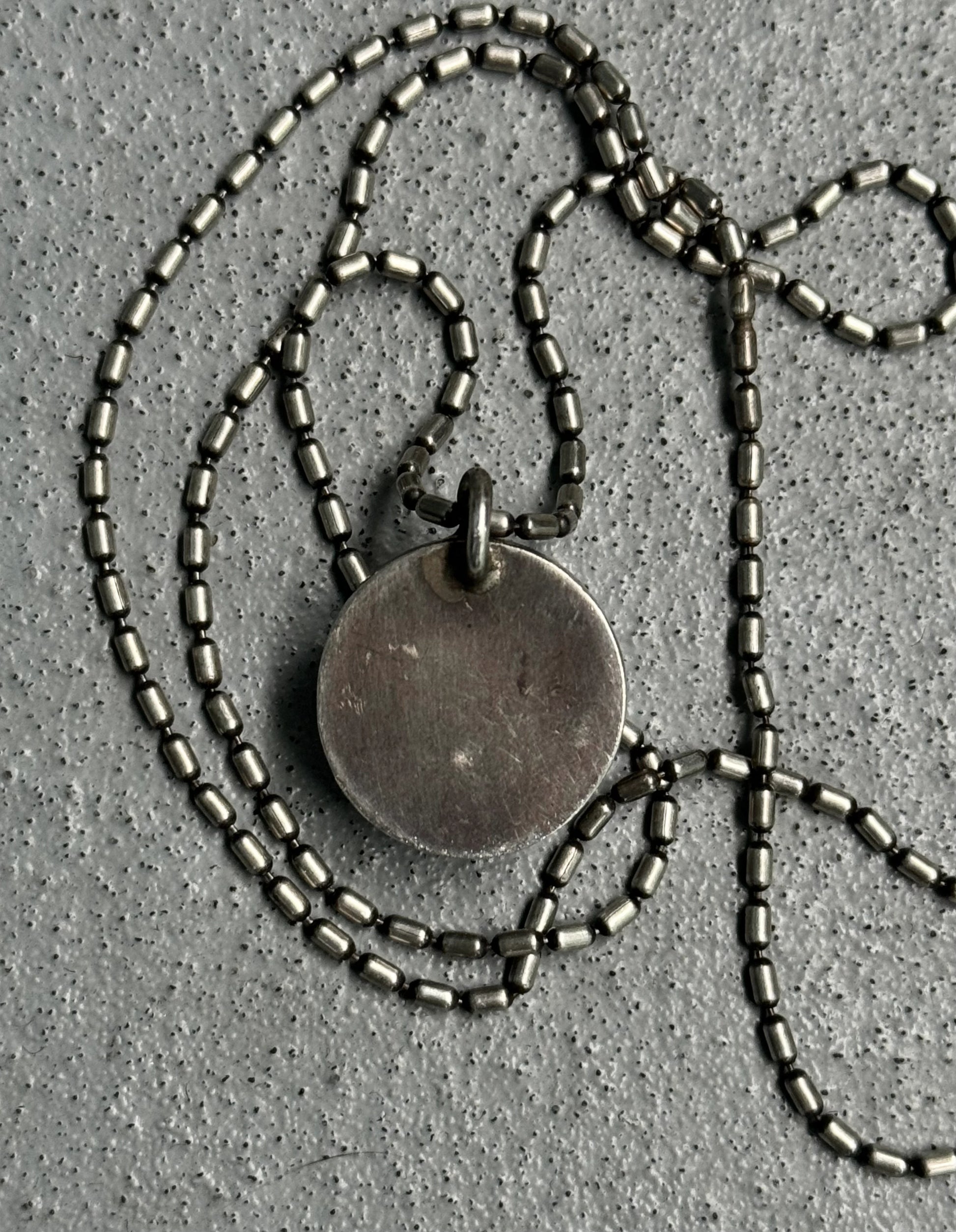 Necklace with a round pendant on a textured gray surface