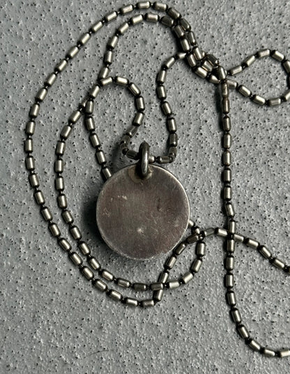 Necklace with a round pendant on a textured gray surface