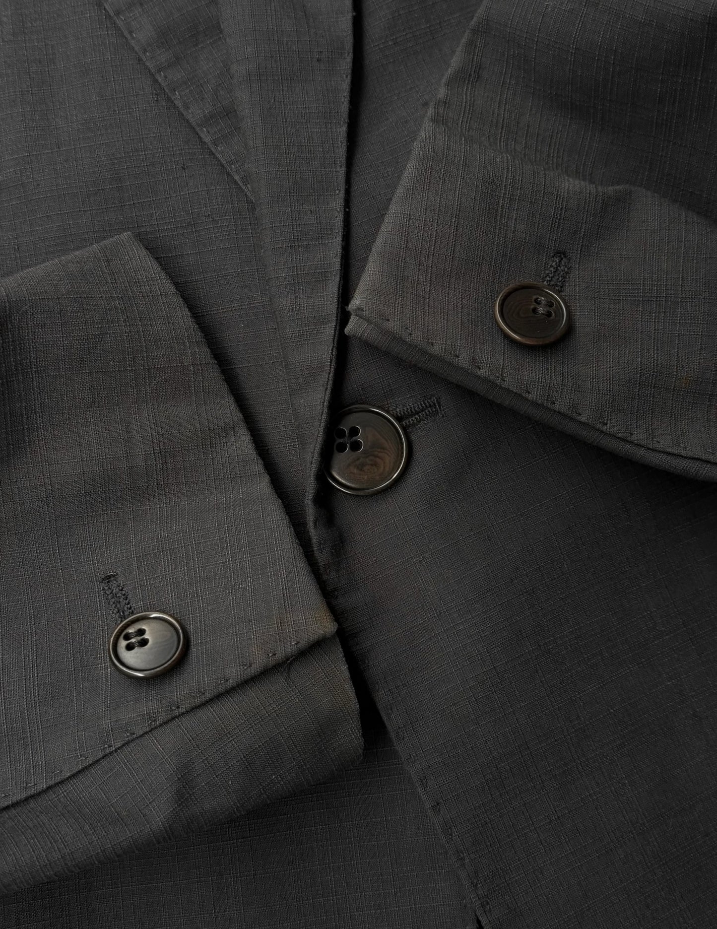 Close-up of a dark gray fabric with buttons on a garment