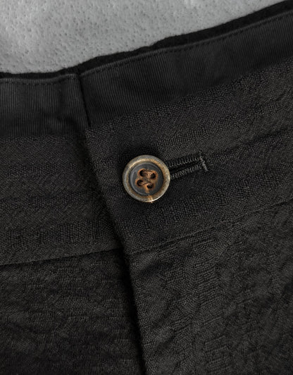 Close-up of a black textured fabric with a button on a gray background
