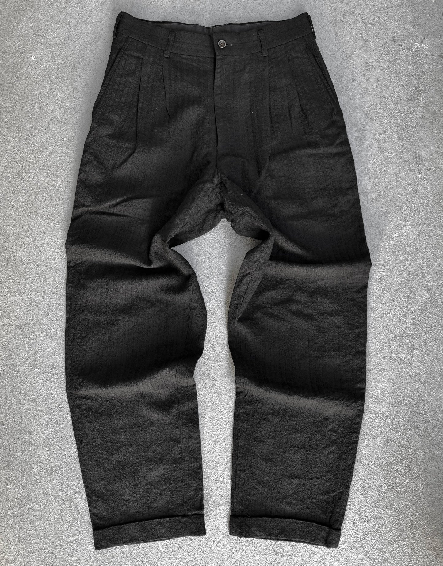 Dark gray pants on a textured gray surface