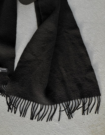Black scarf with fringes draped over a white surface
