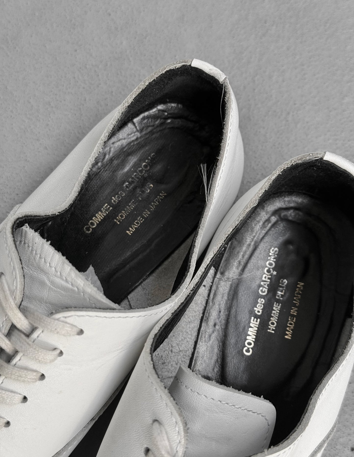 White sneakers with visible brand name on a gray background