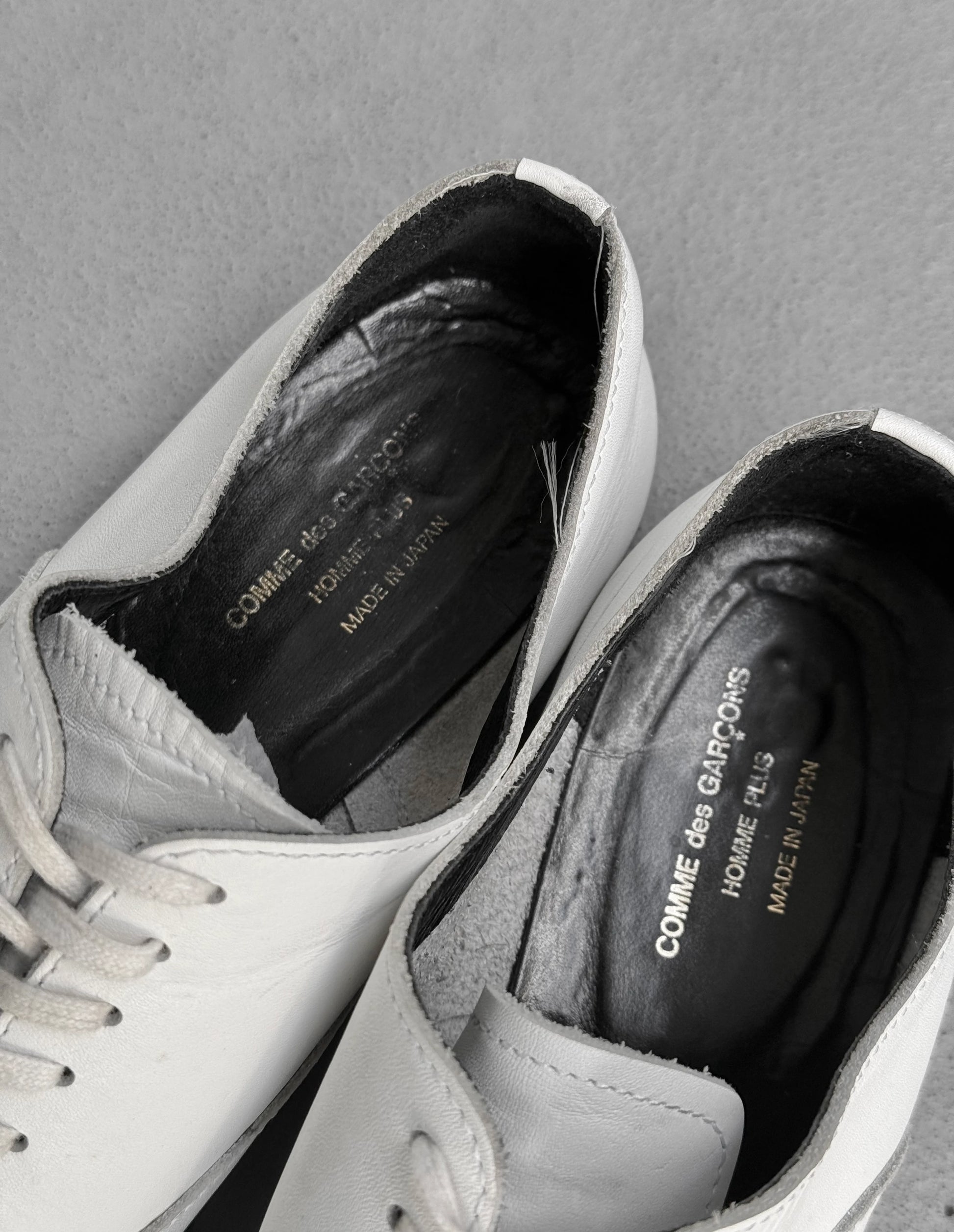 White sneakers with visible brand name on a gray background