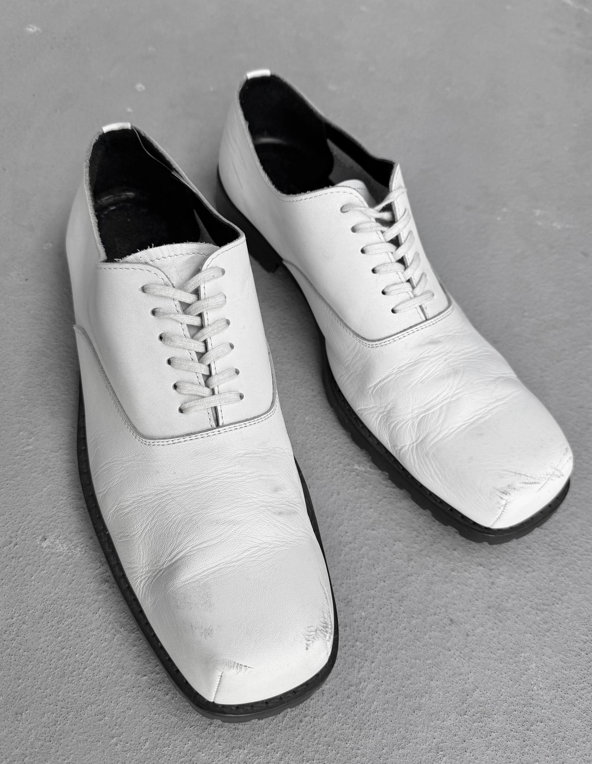 Pair of white dress shoes on a gray surface