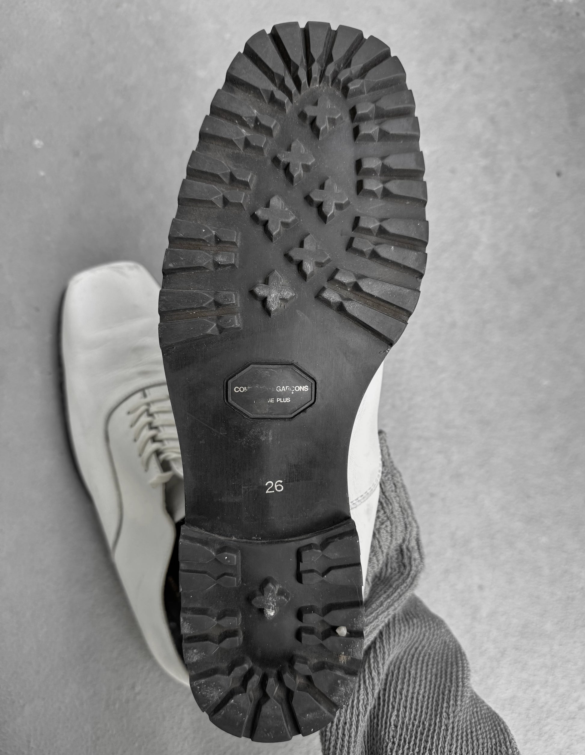 Close-up of a white shoe with black sole on a gray background