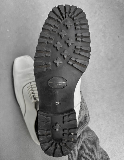 Close-up of a white shoe with black sole on a gray background