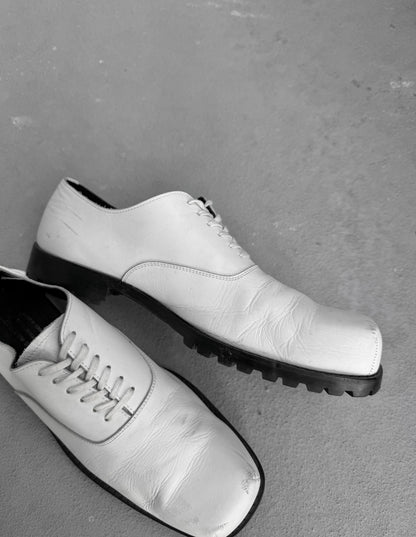 Pair of white leather shoes on a gray surface