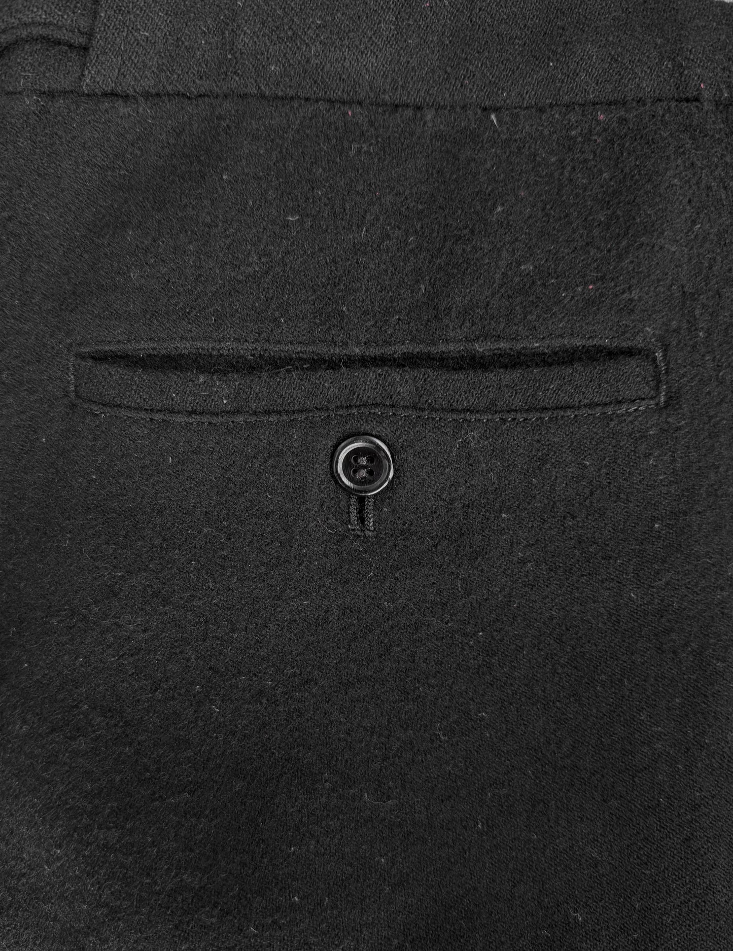 Close-up of a dark gray suit pocket with a button on a matching fabric background